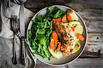 Chicken breast with potatoes and rocket salad on a rustic surface