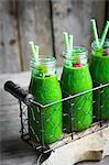 Green smoothies and small glass bottles garnished with raspberries