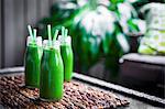 Fresh green smoothie in glass bottles with straws
