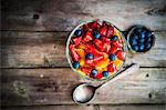 Colourful fruit salad in a jar on rustic wooden surface