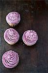 Four blueberry cupcakes on a dark wooden table