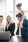 People using laptop, father giving daughter piggyback