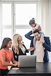 People using laptop, father giving daughter piggyback