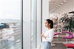 Young woman looking through window in library