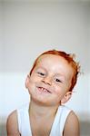 Portrait of a red-haired little boy wearing a tank top smilling, indoors