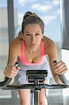 Pretty woman doing spinning bike in fitness center