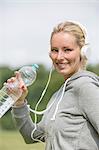 Pretty woman doing sport in park drinking water and smiling at camera