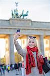 Pretty blonde woman taking a selfie in front of the Brandenburg Gate in Berlin, Germany
