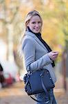 Pretty elegant woman walking with handbag in citycenter and smiling at camera