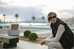 Woman with sunglasses sitting on a bench in citycenter close to the harbour