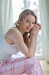 Pretty blonde woman sitting on the bed smiling at camera