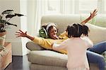 Enthusiastic mother on sofa greeting running daughter