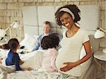 Portrait smiling pregnant woman in bedroom with young family