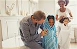 Multi-ethnic parents drying daughters with towels after bath time in bathroom