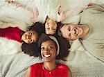 Overhead portrait smiling multi-ethnic young family laying on bed