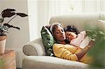 Serene mother and daughter napping and cuddling on sofa