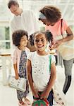 Portrait smiling schoolgirl ready to leave house with family