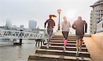 Runners running up sunny urban waterfront steps