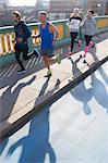 Runners running on sunny urban bridge sidewalk