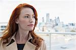 Portrait pensive businesswoman with red hair looking away on urban balcony