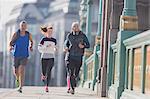 Runners running on sunny urban sidewalk