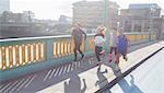 Runners running on sunny urban bridge