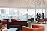 Business people talking at window in urban highrise office lounge with city view