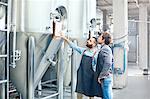 Male brewers checking clipboard on vat