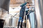 Male brewers checking vat in brewery