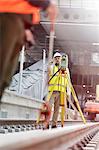 Male engineer using theodolite on tracks at construction site