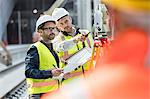 Male engineers using theodolite at construction site