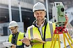 Portrait smiling male engineer using theodolite at construction site