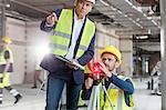 Male foreman and engineer with theodolite at construction site