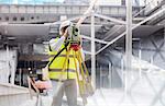 Male engineer using theodolite at construction site