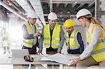 Engineers reviewing blueprints at construction site