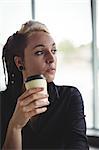 Woman holding disposable coffee cup in café