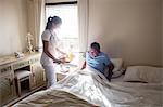 Doctor serving breakfast to senior patient in bedroom