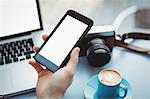 Hand of male executive holding mobile phone in cafeteria