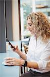 Woman using mobile phone at counter in cafeteria