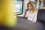 Young woman using laptop inside train compartment