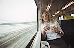 Young woman using mobile phone inside train compartment