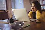 Woman looking at laptop on table at home