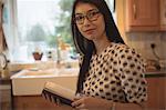 Portrait of woman reading a book in kitchen at home