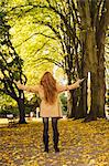 Rear view of woman standing in the park with arms wide open