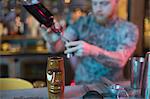 Bartender preparing a drink with bar accessories at counter in bar