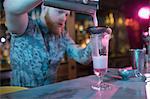 Bartender preparing a cocktail at counter in bar