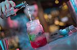 Bartender preparing cocktail at counter in bar