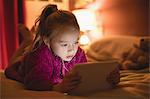 Girl sitting using digital tablet in bedroom at home