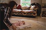 Mother playing with her baby in living room at home