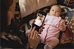 Mother taking her babys picture on mobile phone in living